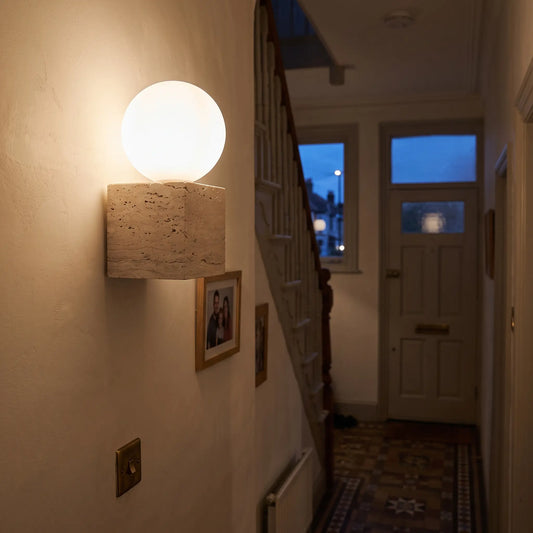 Travertine wall light, glass globe on stone cube, hallway