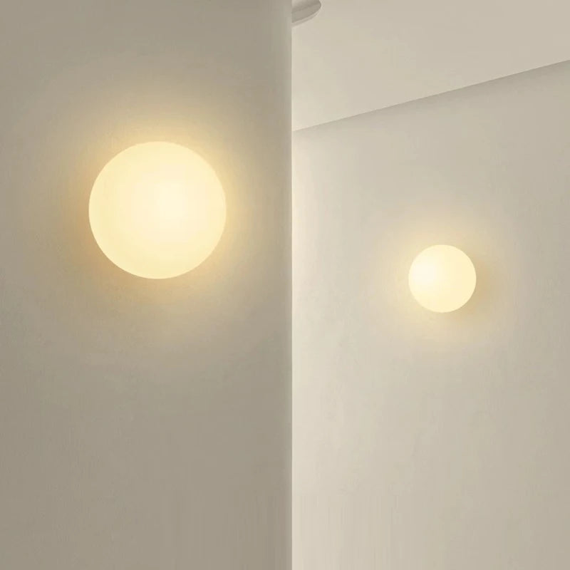 Two milky glass globe wall lights lit on a pale bathroom wall