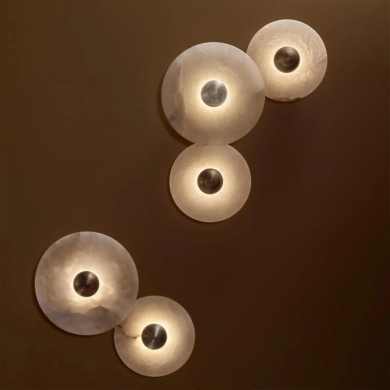 Marble circular wall lights glowing against a warm brown wall