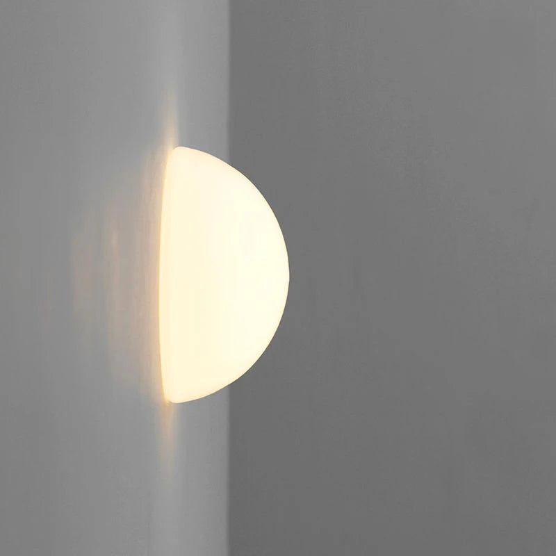 Frosted glass globe wall light casting soft light down a grey wall