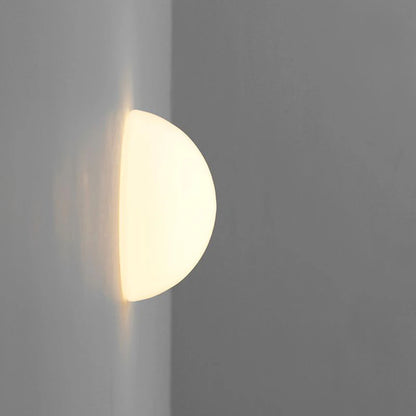 Frosted glass globe wall light casting soft light down a grey wall