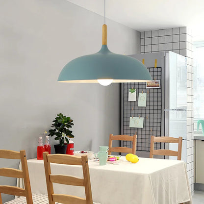 Oak stem pendant light glowing above a bedside table