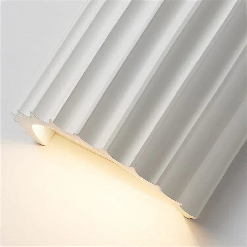 Close up of white curved resin wall light showing fluted ribs and soft glow