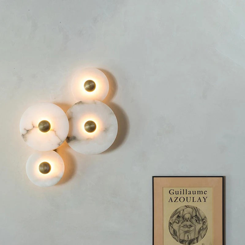 Cluster of marble circular wall lights lit on a pale living room wall