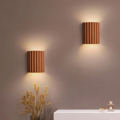 Pair of terracotta resin wall lights washing light up a bedroom wall