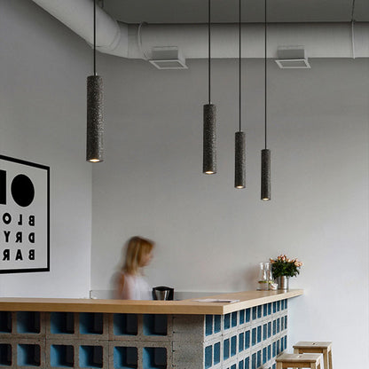 Terrazzo tube pendants in a row over a café counter
