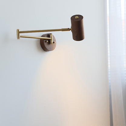 Walnut swing arm wall light with brass arm, lit