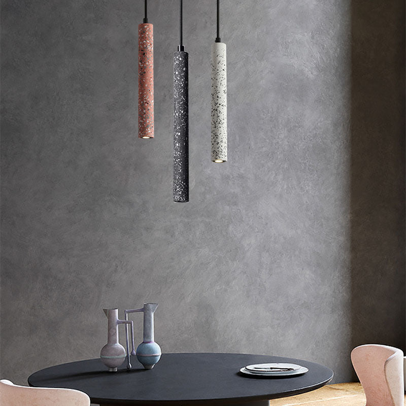 Terrazzo tube pendants lit against a concrete wall