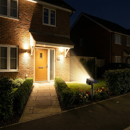 Solar garden spotlight illuminating landscaping at dusk