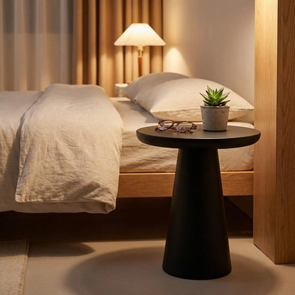 Round side table in matte black finish styled as a bedside table in a modern bedroom setting