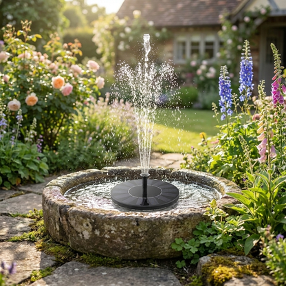 Solar fountain pump floating in stone garden fountain spraying water in sunny cottage garden