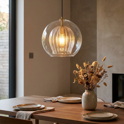 June glass globe pendant light hanging over a modern dining table at dusk