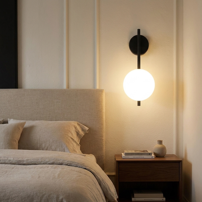 Black glass wall sconce beside a bed
