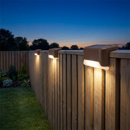 Brown solar deck lights with warm white glow on a fence top
