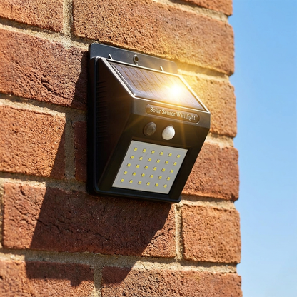 Solar security light charging in daylight on a brick wall