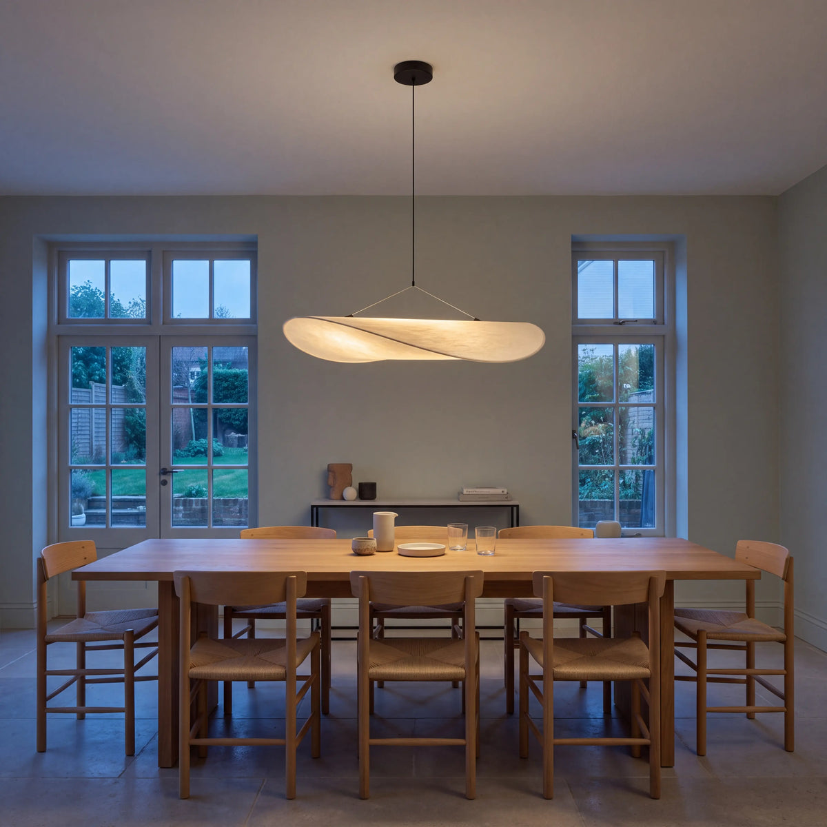 Designer pleated silk pendant light with brushed metal frame, hanging over a UK dining table