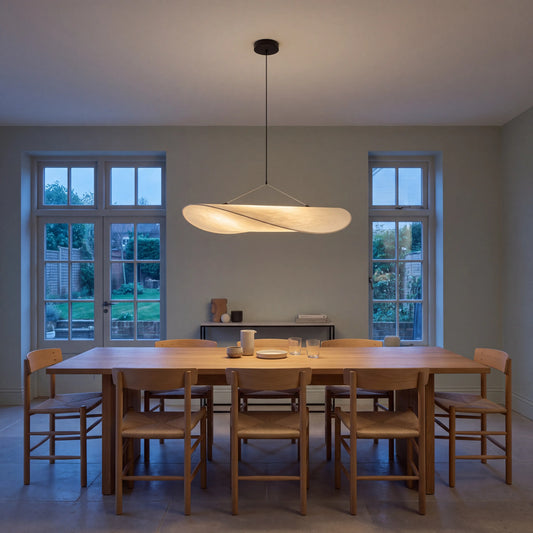Designer pleated silk pendant light with brushed metal frame, hanging over a UK dining table