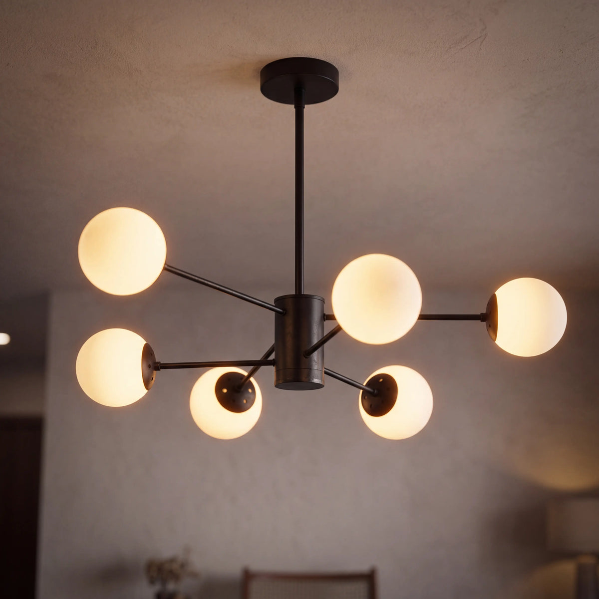 Modern glass globe chandelier with 6 lights and a black frame, lit above a living room