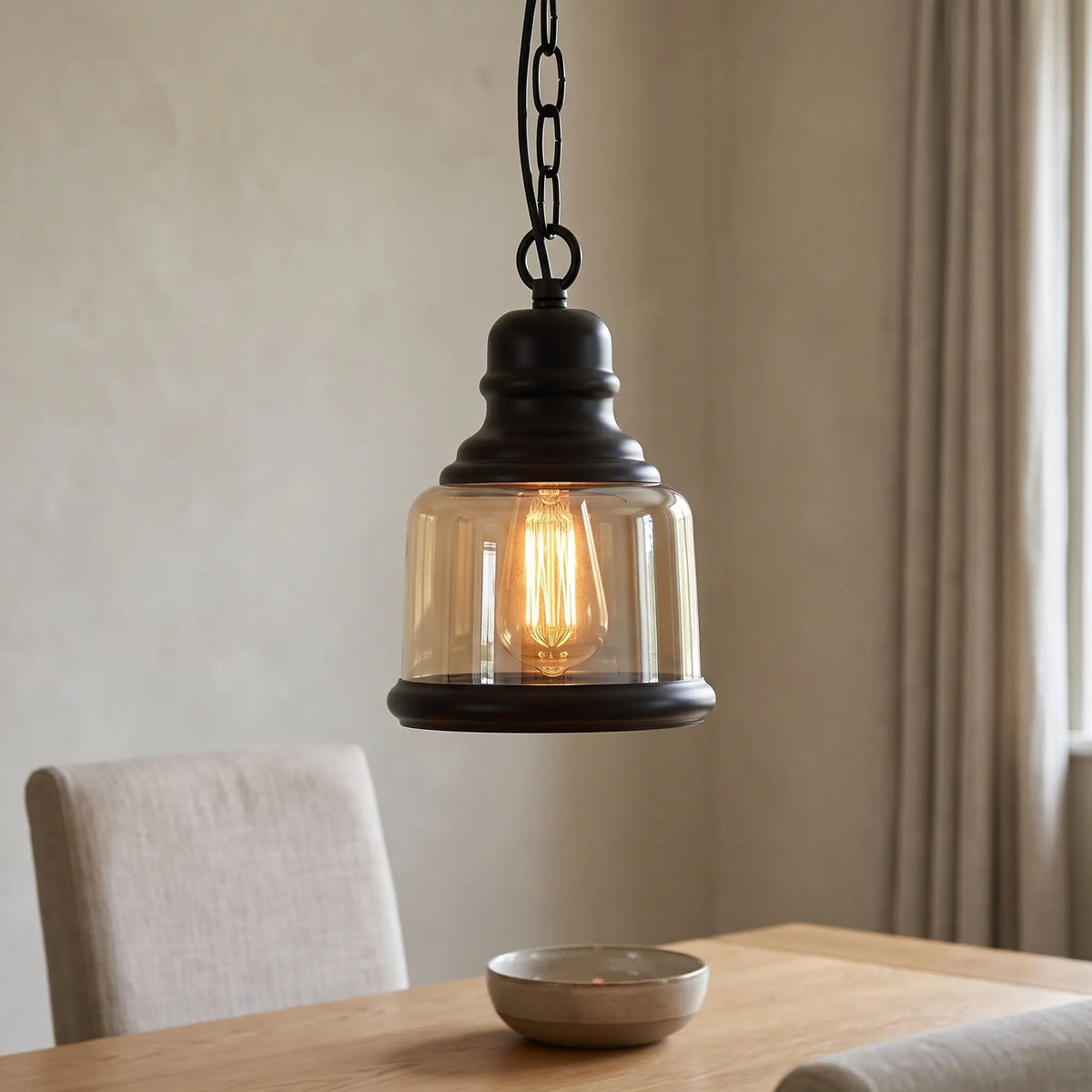 Amber glass industrial pendant light – Bell shade – over a dining table
