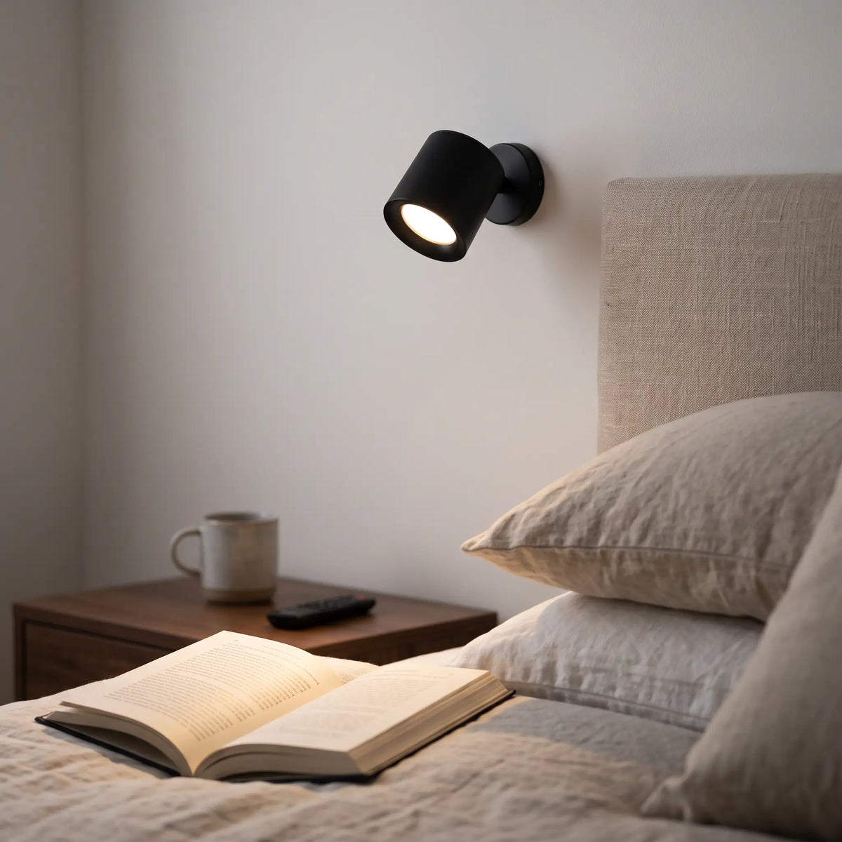 Black rechargeable magnetic reading spotlight on a bedroom wall beside the bed