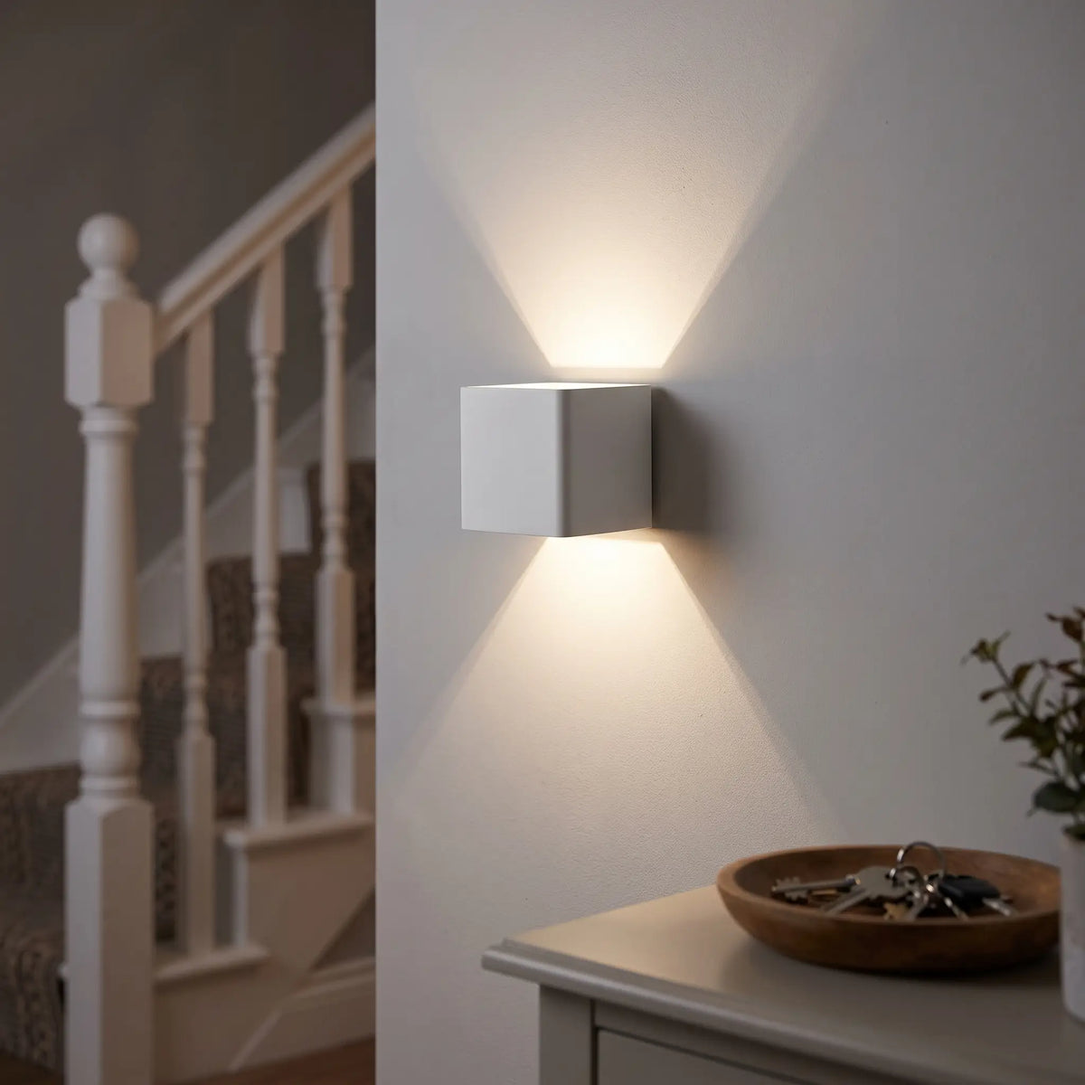 White cube up and down wall light on a hallway wall by the stairs