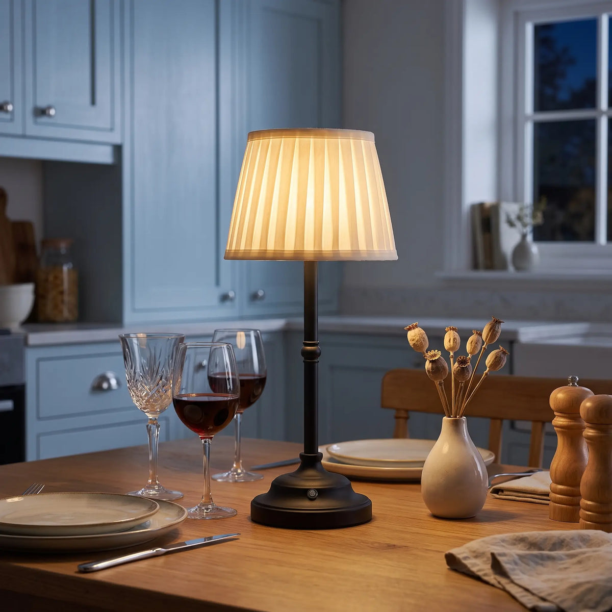 Black cordless table lamp with cream pleated shade on a dining table