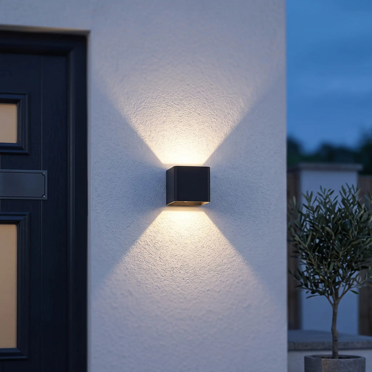 Black cube up and down wall light beside a front door at dusk
