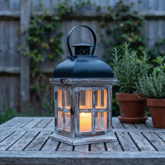 Wooden candle lantern with black roof on a garden table at dusk, 21cm