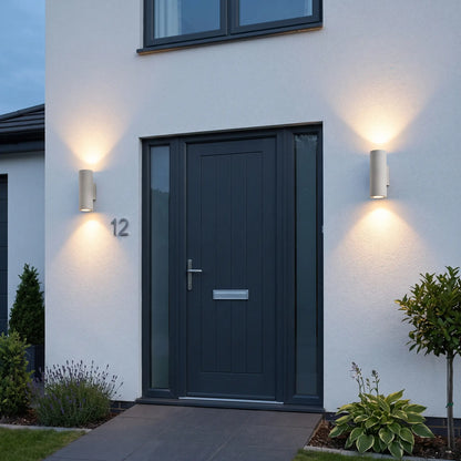 Round sand white up down outdoor wall lights either side of a front door at dusk