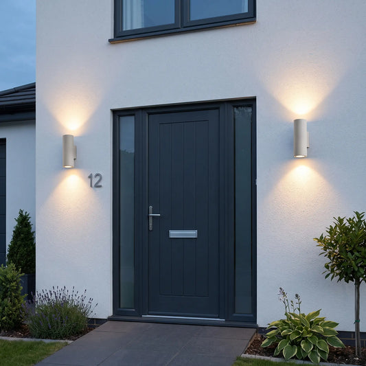 Round sand white up down outdoor wall lights either side of a front door at dusk