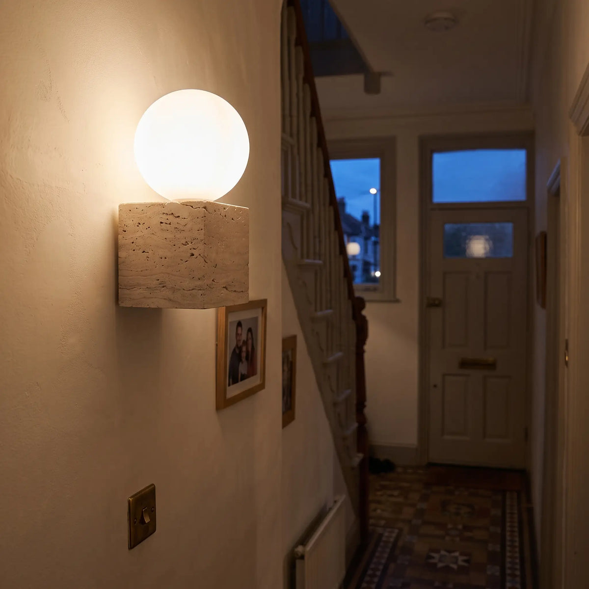 Travertine wall light, glass globe on stone cube, hallway