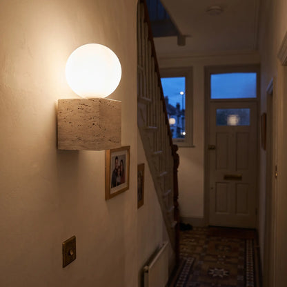 Travertine wall light, glass globe on stone cube, hallway
