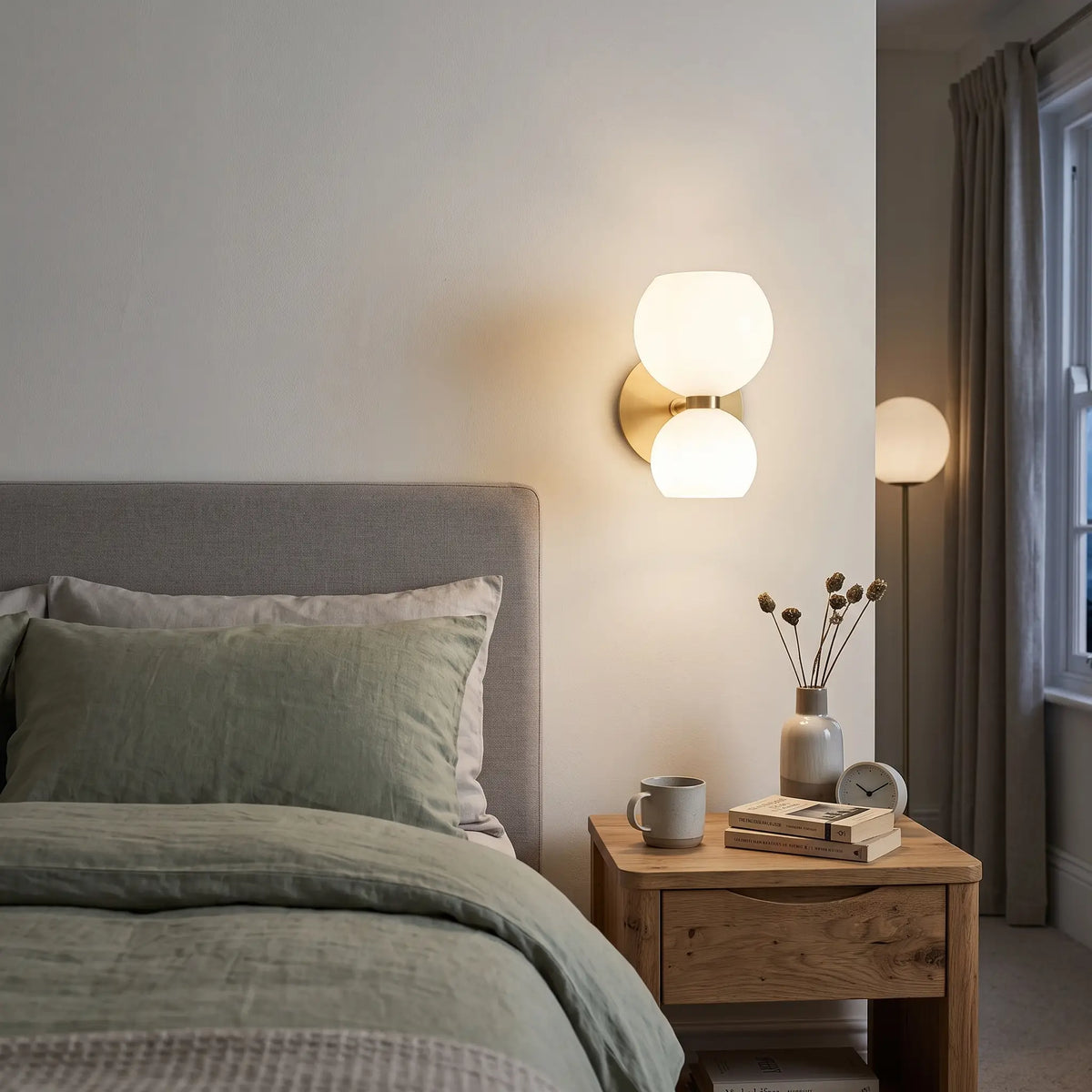 White glass hourglass wall light above a bedside table