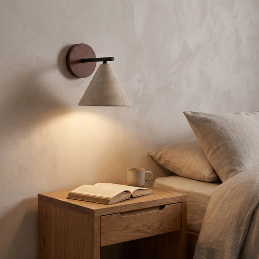 Travertine stone cone wall light with wooden backplate above a bedside table