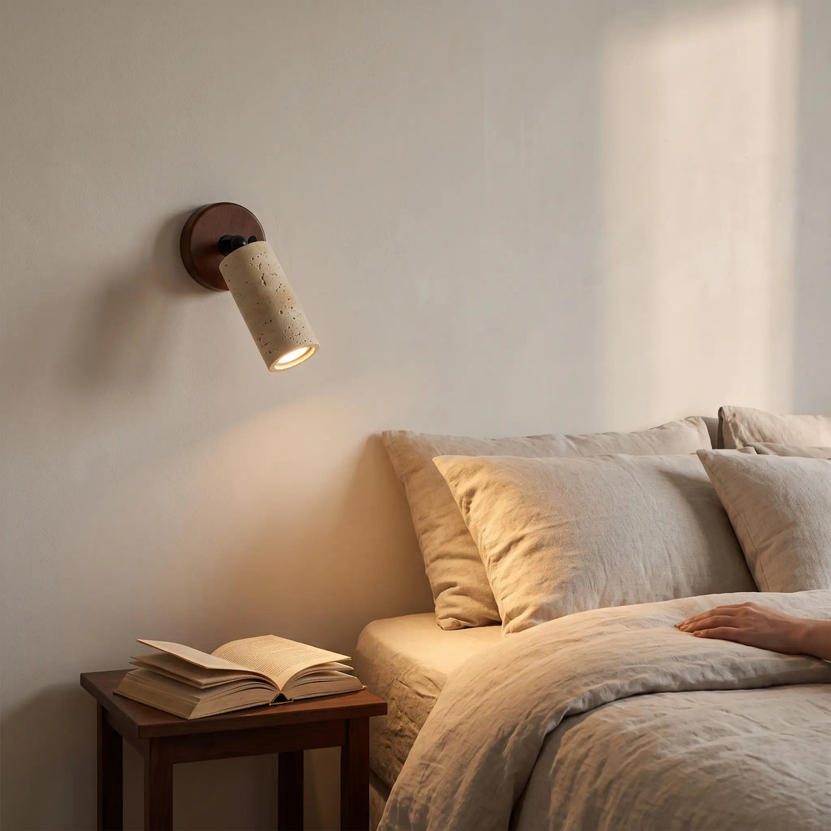Stone spotlight travertine wall light angled over a bed, lit warm