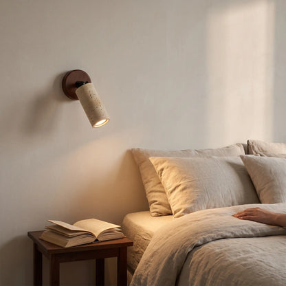 Stone spotlight travertine wall light angled over a bed, lit warm