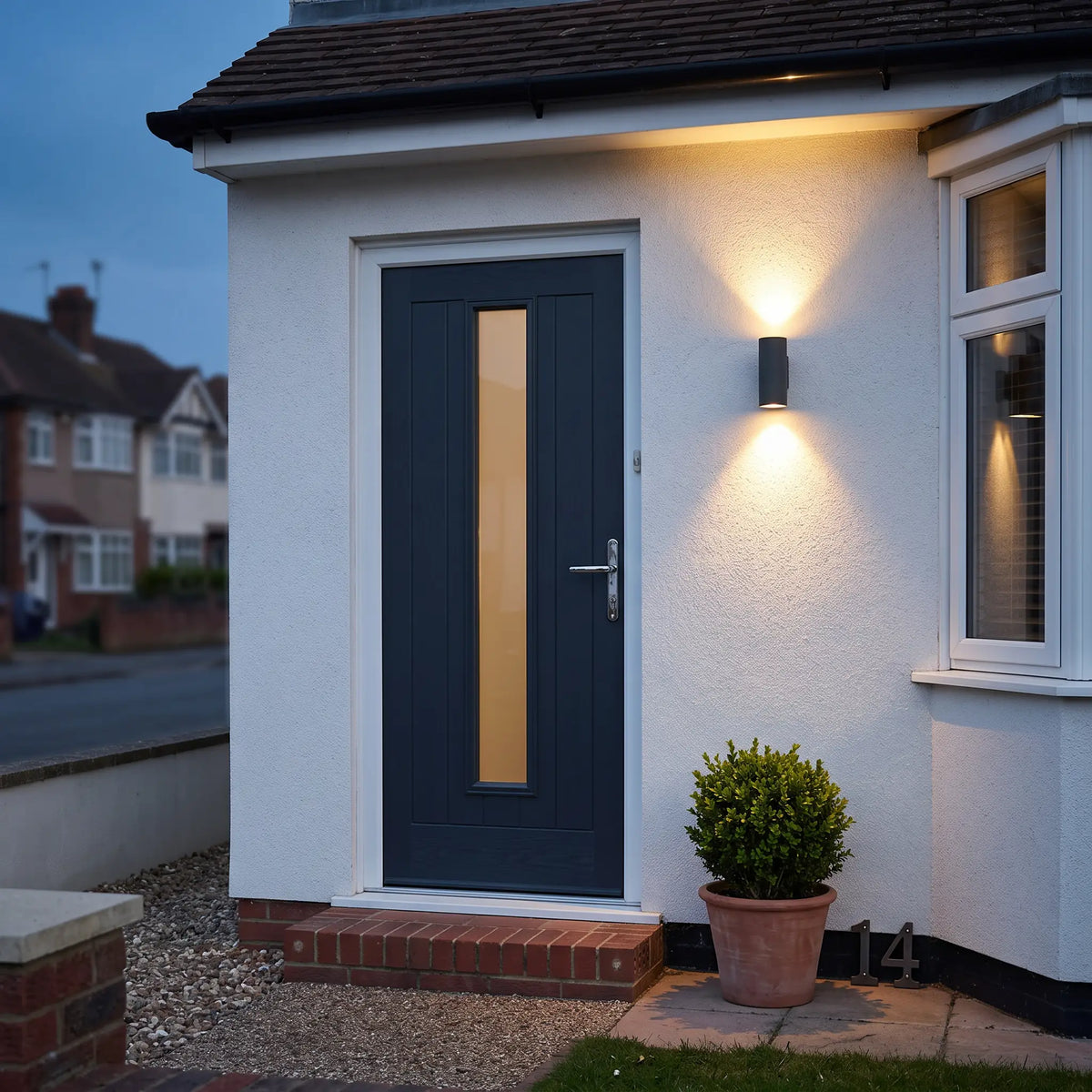 Round sand black up down outdoor wall light beside a front door at dusk