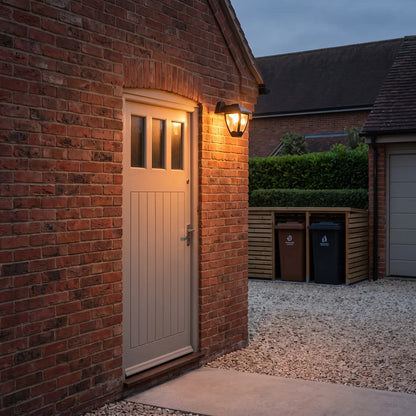 Black hanging coach lantern above a garage side door at dusk