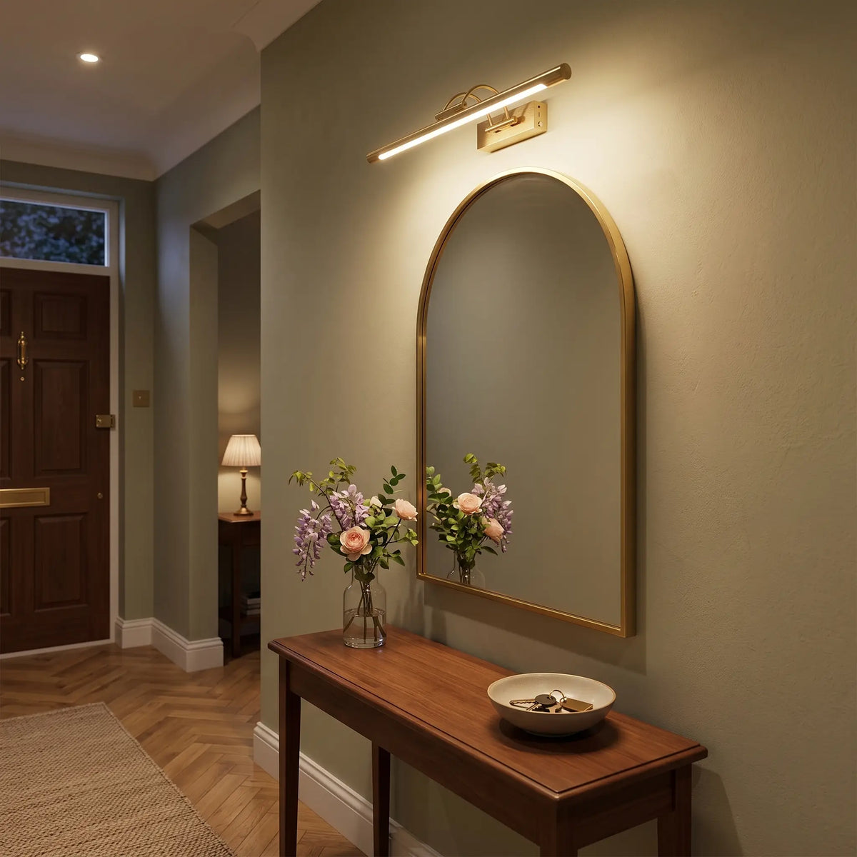 Brass rechargeable picture light above a hallway mirror, lit