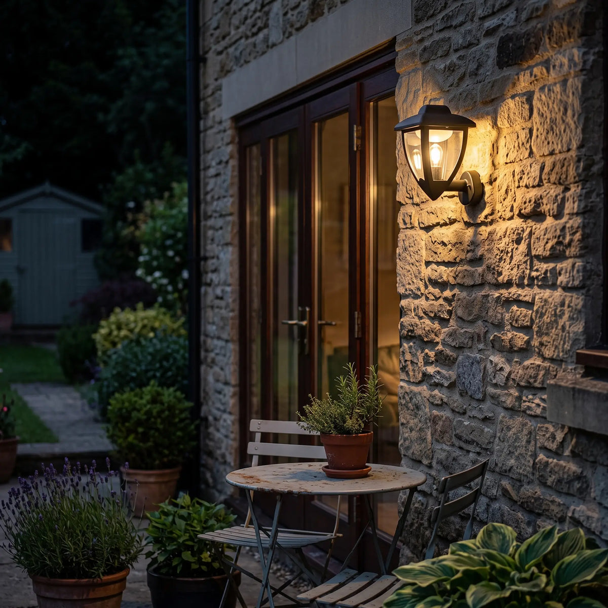Black coach lantern on a patio wall beside a bistro table at night