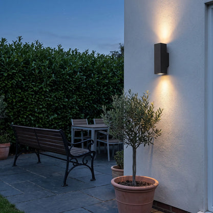 Square sand black up down outdoor wall light on a garden patio wall at dusk
