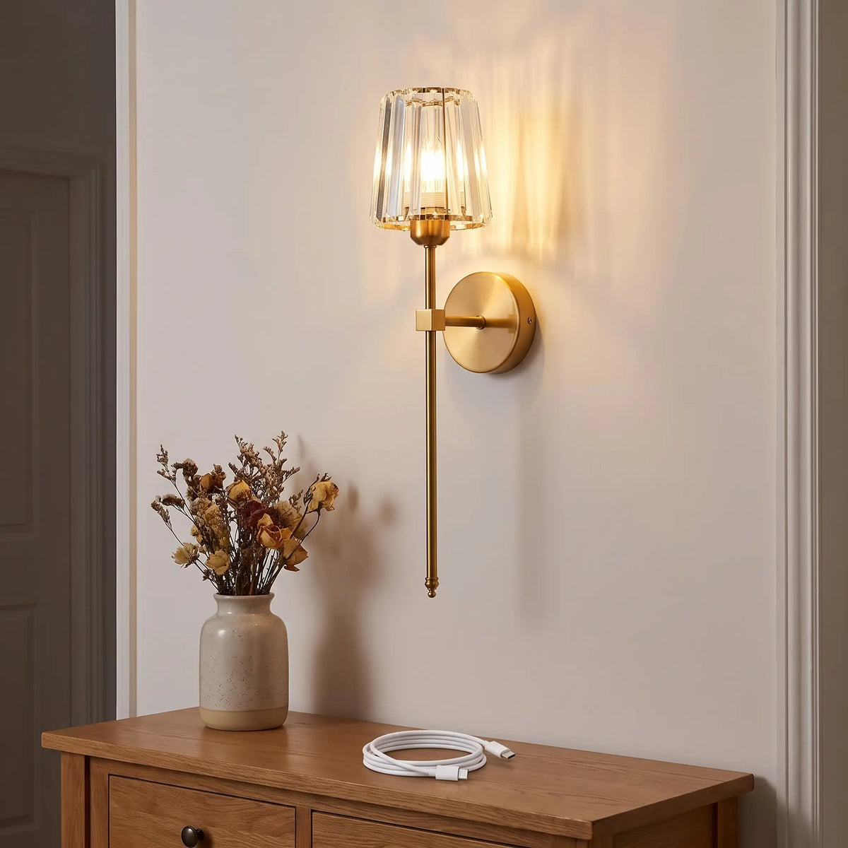 Gold crystal rechargeable wall sconce on a clean hallway wall with no wiring, USB-C charging cable on the table