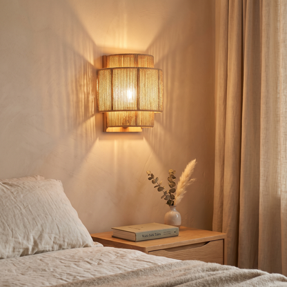 Tiered natural rope wall light glowing above a bedside table