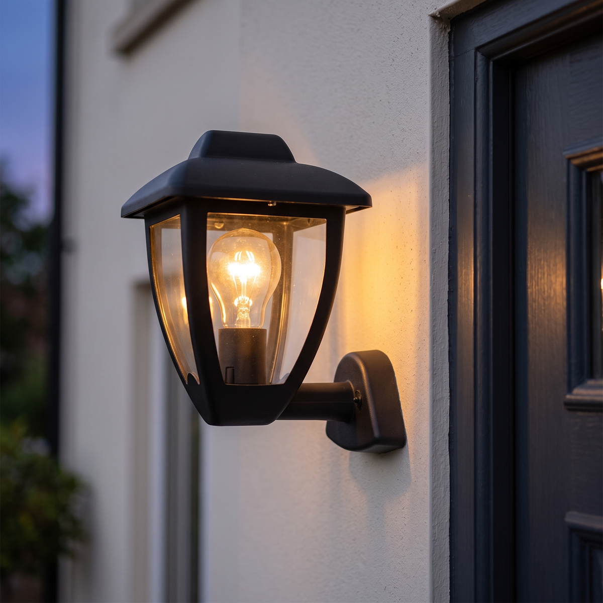Black upright coach lantern lit beside a front door at dusk, close-up