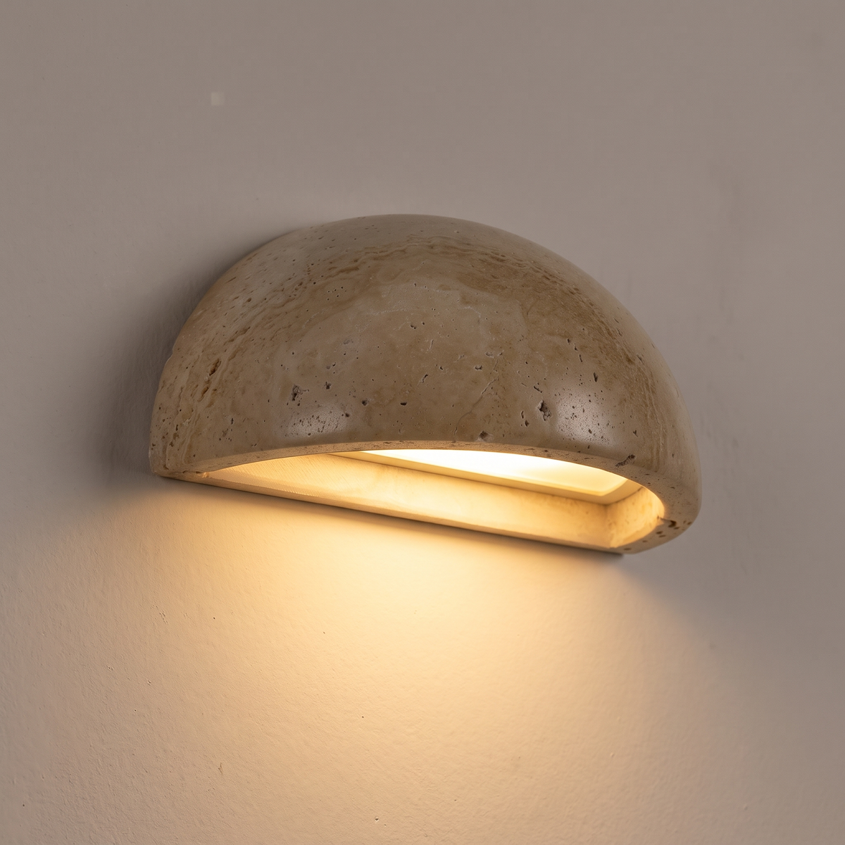 Close-up of half moon travertine wall light shining light downwards