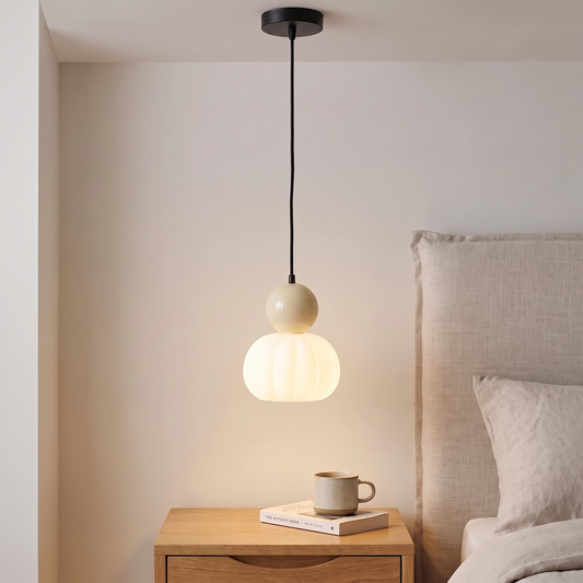 Pumpkin ribbed glass pendant light with cream ball knob, lit at a bedside