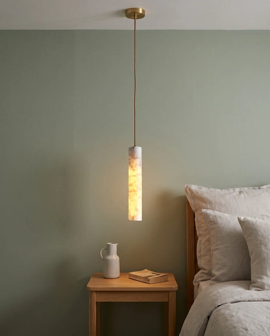 Marble Cylinder Pendant Light in brushed brass, hanging above a bedside table in a sage-green bedroom