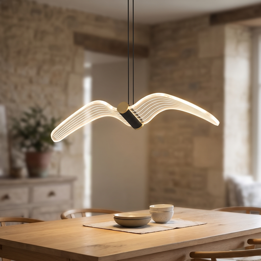 LED bird pendant light with black and gold frame, lit above a dining table