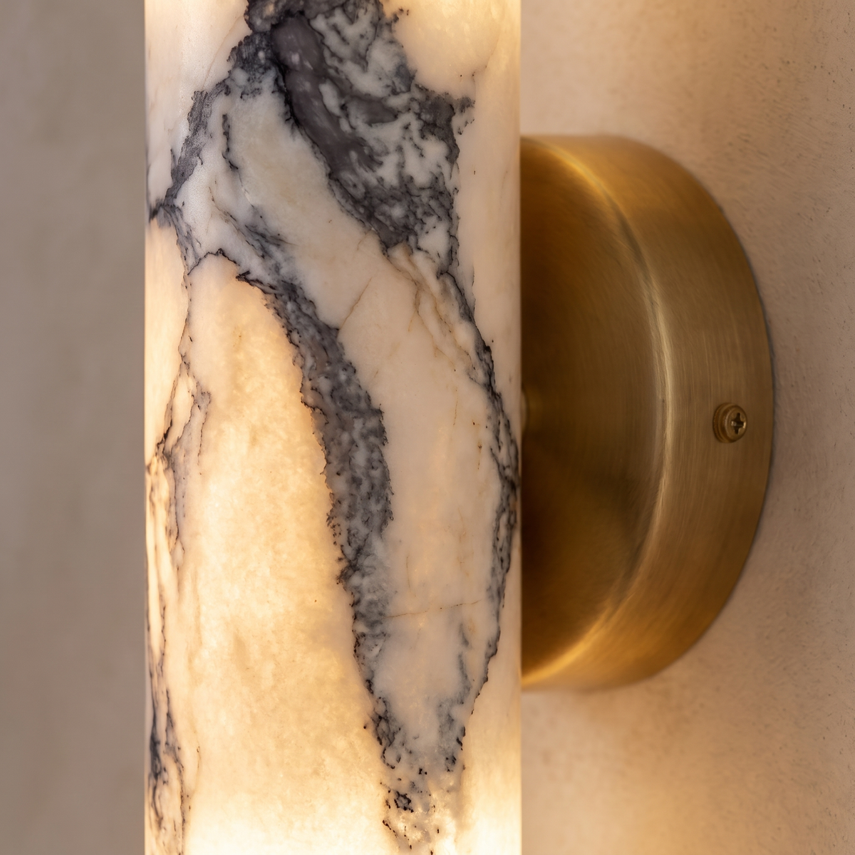 Close-up of the marble veining and brass back plate on the up and down wall light, lit