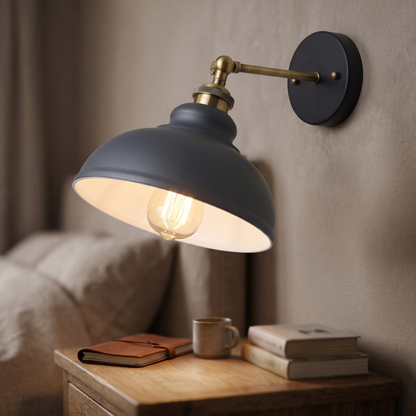 Vintage industrial dome wall light in grey with brass-tone adjustable arm, lit above a bedside table